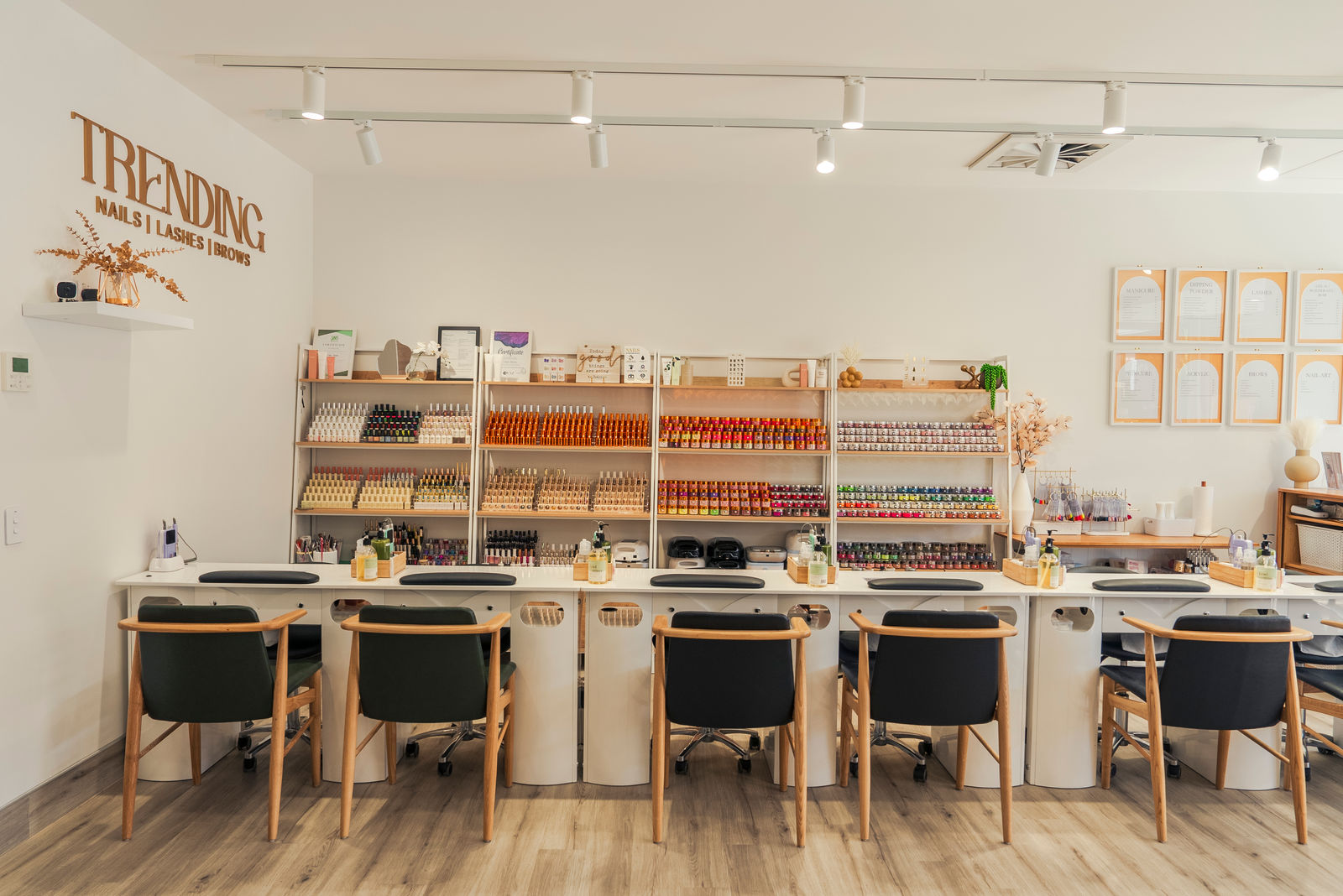 Inside Trending Nails and Beauty: manicure stations in front of a wall of nail polish